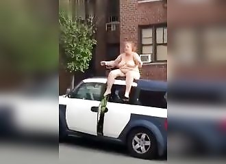Nue, cette femme crie sa colère assise sur une voiture !