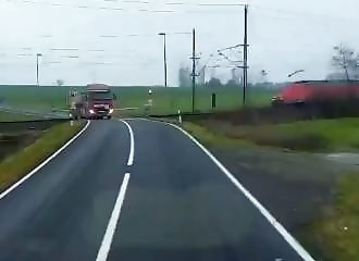 Dangerous escape for a truck driver trapped at a level crossing, shortly before a collision with a freight train