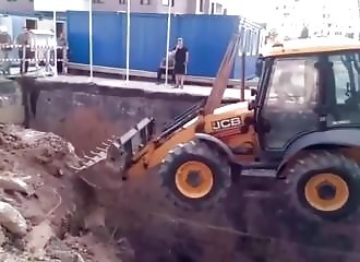 Une grue tente de descendre une tractopelle dans un fossé (FAIL)
