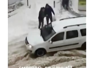 Deux hommes aident une voiture coincée dans la neige