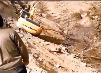 Deux hommes retiennent une pelleteuse pour qu’elle ne tombe pas dans le vide