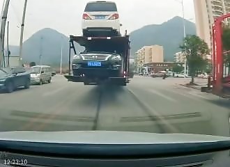 A truck hooks onto a car and drags it along without noticing.