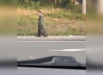 Smiling, he walks with a dead raccoon