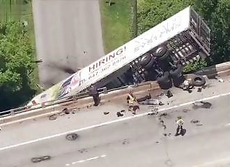 A truck full of tomatoes ends up suspended from a bridge