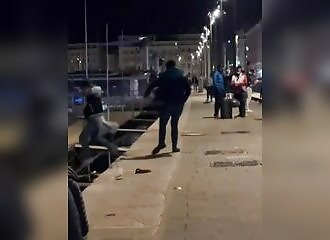 One man pushes another in a harbor while urinating