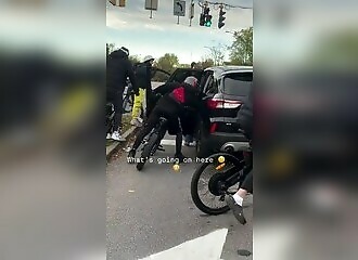 A gang of bikers attempt to rob a motorist by entering her car at a red light