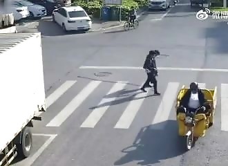 A man crossing the street is caught by a rope dragged by a tricycle